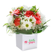 Captured with a sense of joy and abundance, this fresh bouquet from Cowley Florist stands upright in a crisp, modern white gift bag, isolated against a luminous white background-the kind of presentation that could brighten any home along Church Cowley Road. Waves of lush, coral and soft peach carnations fill the heart of the arrangement, their frilled, velvety petals full of cheerful color and gentle movement. Among these blooms, snowy-white daisies with vivid yellow-green eyes bring a sunny playfulness, while dainty sprays of white baby's breath float like soft clouds throughout, evoking innocence and lightness. Nestled subtly within the bouquet's depths, hints of unopened purple buds lend both anticipation and dimension, drawing the eye and inviting closer appreciation. Framing the flowers, an enveloping layer of rich green, glossy leaves fans out gracefully, reminiscent of the vibrant foliage in Cowley's green spaces. The entire bouquet forms a rounded, harmonious shape-intentionally full and perfectly balanced for a sense of quiet celebration. The sturdy white ribbon handles of the bag promise easy delivery or gifting, ideal for birthdays, anniversaries, or simply saying thank you to someone dear in Cowley. This thoughtfully arranged bouquet is a true reflection of the care, artistry, and warmth that Cowley Florist brings to every local occasion.